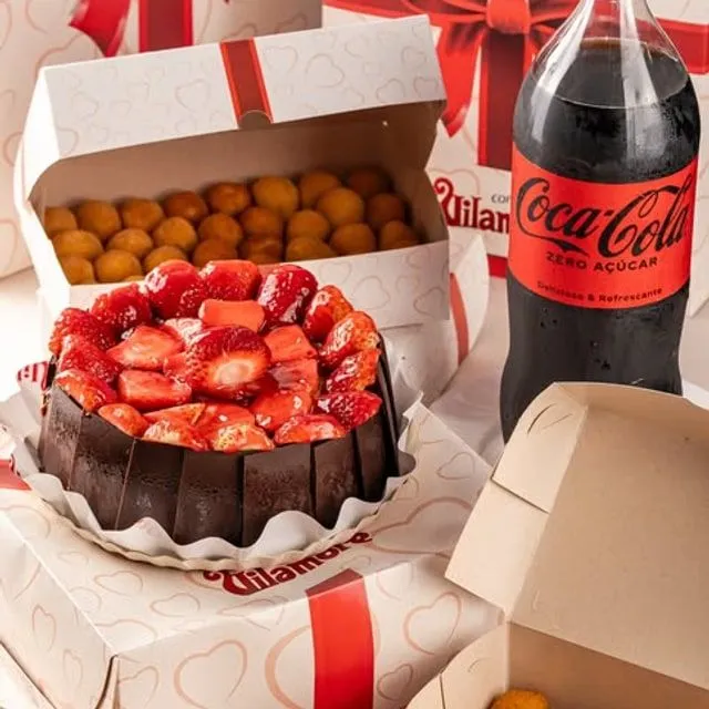 Kit festa da Vilamore: torta de morango, refrigerante e caixas de salgadinhos nas embalagens da casa.