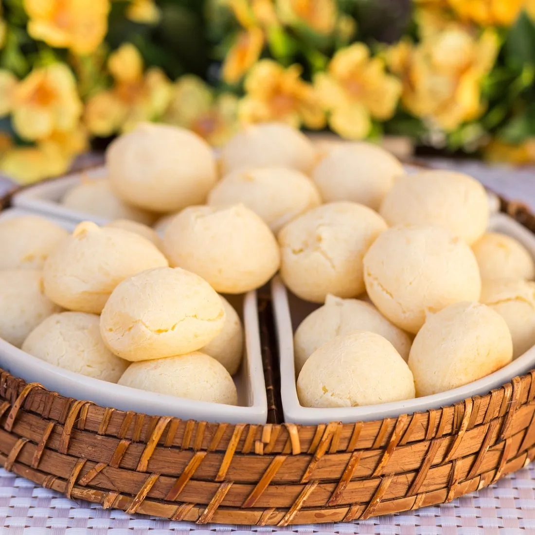 Travessa de vime com pães de queijo dourados da Vilamore.