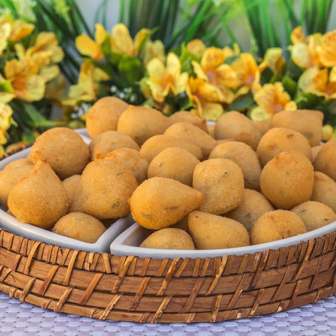 Travessa de vime cheia de salgadinhos de festa fritos da Vilamore.