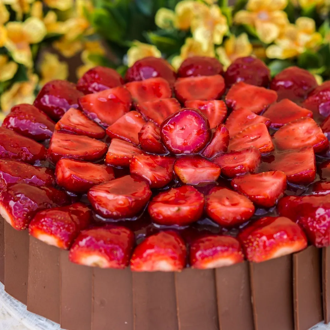 Torta da Vilamore coberta de morangos com brilho, com a lateral revestida de placas de chocolate.